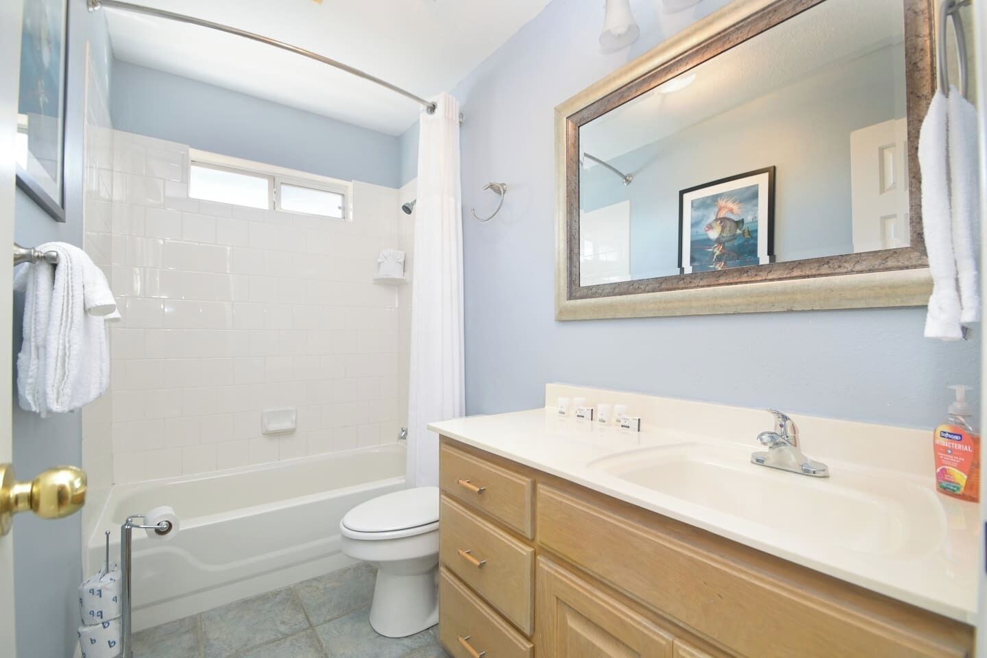 A bathroom with a shower, toilet, vanity with drawers, and a mirror.