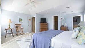 A bedroom with a bed, dresser, chair, television, and ceiling fan. - Views! Near Lake - Hot tub - King Mstr w/ Balcony (Canyon Lake)