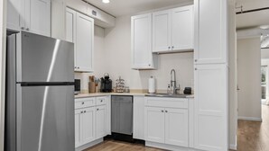 Una cocina moderna con armarios blancos, electrodomésticos de acero inoxidable y piso de madera.
