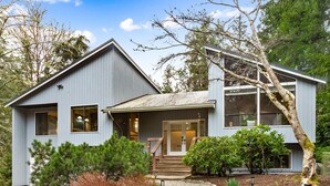 A modern two-story house with a front porch, a staircase, and a well-maintained garden.