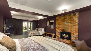 A bedroom with a bed, a fireplace, a window, and a door.