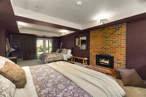 A bedroom with a bed, a fireplace, a window, and a door. - Designer Forest Retreat with Fireplaces & Deck (Bainbridge Island)
