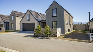 A modern residential area with houses featuring gabled roofs and large windows. - Miharo Mountain Haven | Mountain Views & Outdoor Fire (Wānaka)