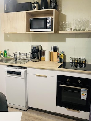 A compact kitchen with a microwave, coffee maker, and oven.