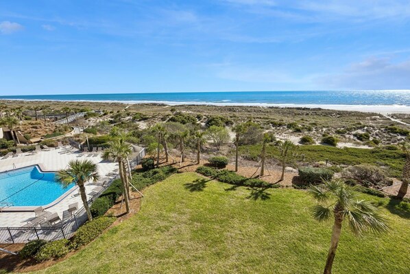 Área da piscina com vista para a praia e o oceano.