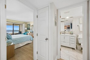 Quarto com cama, vista para o mar, banheiro com vaso sanitário e área de cozinha.