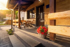 A wooden building with a porch, outdoor seating, and a welcome sign.
