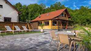 Une terrasse avec des fauteuils, une table et une bouteille de vin.