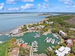 An aerial view of a marina with boats docked, a lighthouse, and surrounding buildings. - Harbour Town Villa, Walk to Marina & Golf Links, South Beach Pool Pass, 3 Bedrooms! (Hilton Head Island)