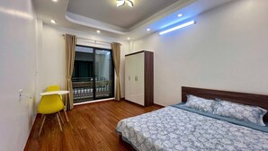 Ein Schlafzimmer mit Bett, Sessel, Kleiderschrank und einem Balkon mit Vorhängen.