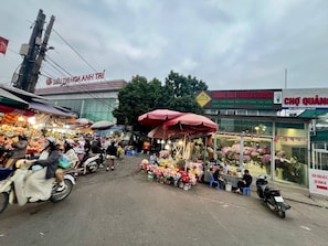 A street market with various stalls, including one selling flowers and another with a sign for 'TRUNG XUAN FLOWER & BONSAI'. - Spacious 7-bedroom house in marvelous Hà Nội with AC (Hà Nội)