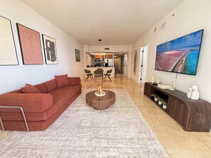 Ein modernes Wohnzimmer mit einem roten Sofa, einem Couchtisch, einem Fernseher und Kunstwerken an den Wänden.