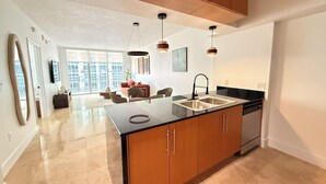 Een moderne keuken met een centraal eiland, hangende verlichting en uitzicht naar buiten.