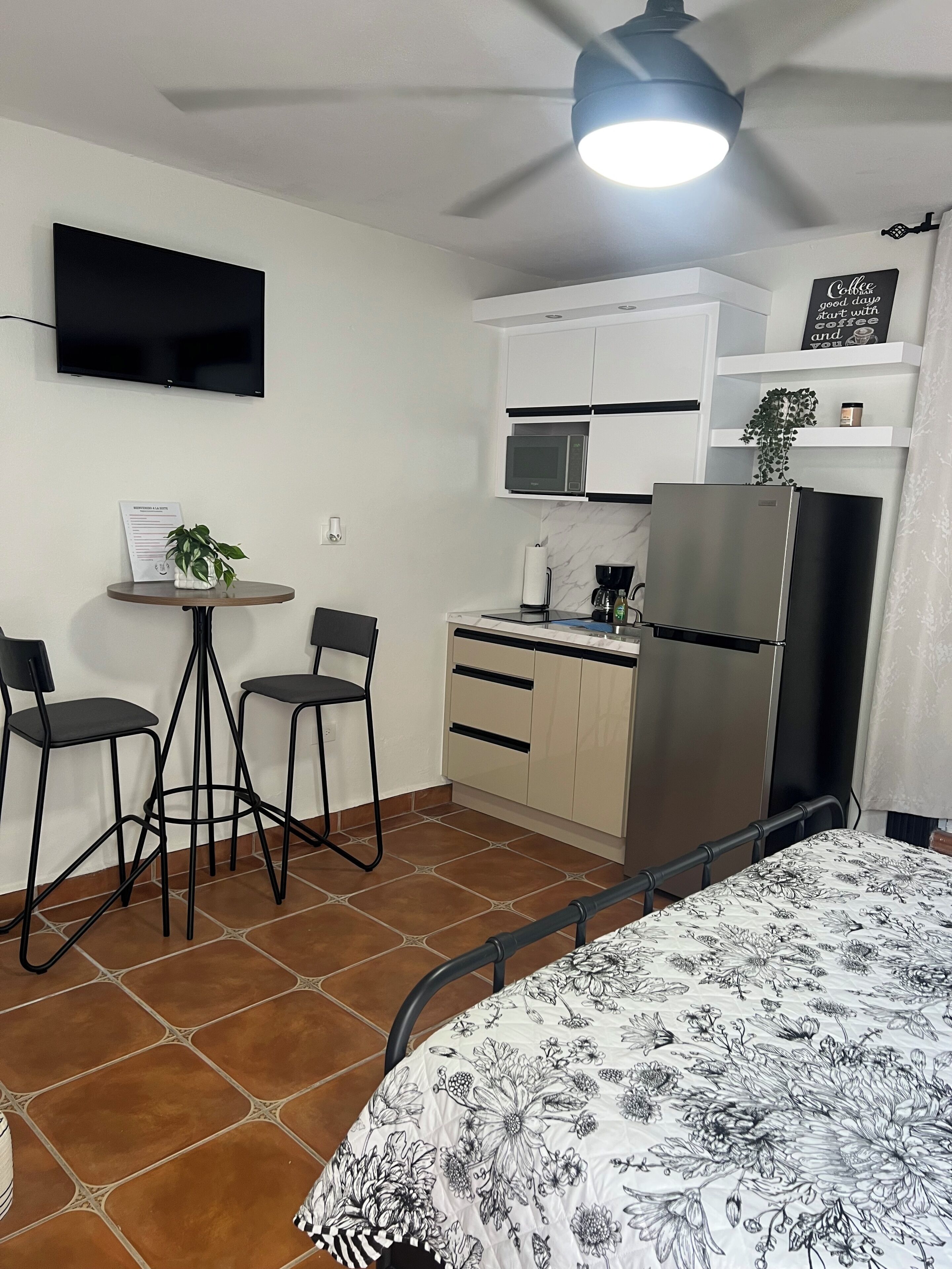A compact kitchenette with a microwave, refrigerator, and a small dining area with two chairs and a table.