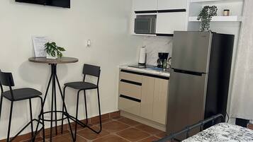A compact kitchenette with a microwave, refrigerator, and a small dining area with two chairs and a table.