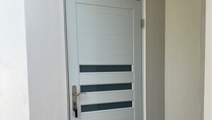 Une porte blanche ornée de lignes horizontales, avec le chiffre « 1 » au-dessus, qui donne sur un hall d’entrée carrelé.
