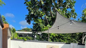 Une terrasse extérieure dotée d’un espace salon, d’une pergola et offrant une vue sur la végétation environnante.