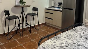 Une cuisine compacte équipée d’un four à micro-ondes, d’un réfrigérateur et d’un petit coin repas avec deux chaises et une table.