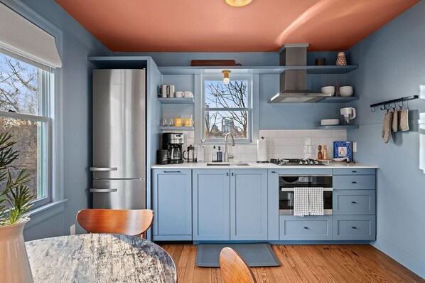 A kitchen with blue cabinets, a stainless steel refrigerator, and a window with a view. - Ted & Breakfast - Full Duplex Property (Austin)
