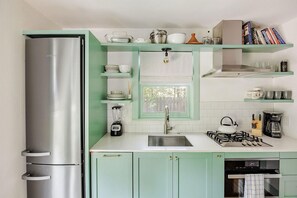 Une cuisine compacte équipée d’un réfrigérateur intégré, d’une cuisinière à gaz et d’un évier.