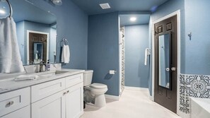 Un baño con lavamanos, espejo y retrete.