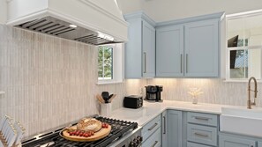 Eine moderne Küche mit Gasherd, Kaffeemaschine und hellblauen Schränken.