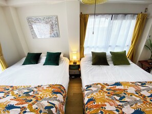 Hotellihuone, jossa on kaksi sänkyä, seinällä kartta, yöpöytä ja ikkuna, jossa on verhot.