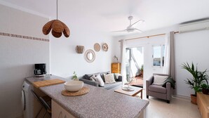Cocina moderna con encimera de granito, cafetera y zona de comedor con sofá y una silla.
