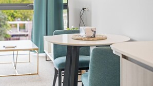 Une pièce moderne avec une table ronde, des chaises de couleur turquoise et une vue sur la verdure à l’extérieur.