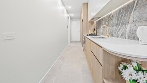 Een moderne keuken met een marmeren spatwand, houten kastjes en een wit aanrecht.