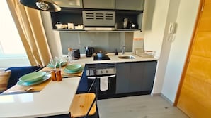 Une cuisine de taille réduite, équipée d’une cuisinière, d’un évier et d’un plan de travail.