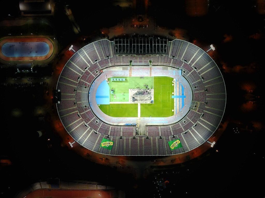 Een stadion met een veld in het midden, meerdere zitrilen en een baan rond het veld.