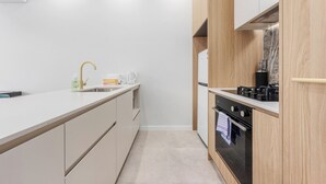 Een moderne keuken met een wit aanrecht, een spoelbak, een kookplaat en houten kastjes.