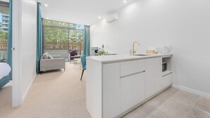 Een moderne keuken met een centraal eiland, een spoelbak en een raam met uitzicht op een balkon.