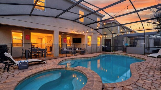 A pool area with a glass-enclosed patio, outdoor seating, and a grill. - Shiva by Avantstay Sleeps 22 Pool + Hot Tub + Great Park Access (Kissimmee)