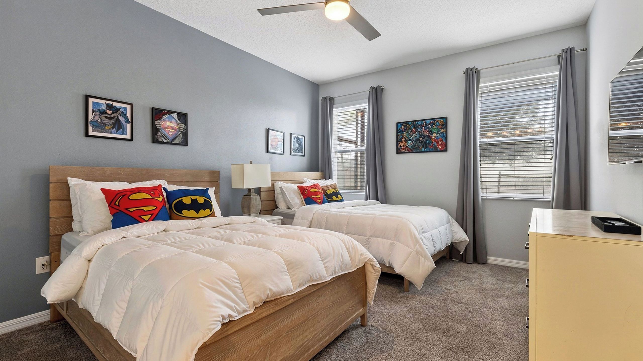 A bedroom with two beds, a ceiling fan, and artwork on the walls.