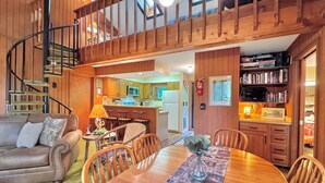 Un salon chaleureux avec une table à manger en bois, un canapé et un escalier menant à l’étage supérieur.
