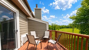 Une terrasse dotée de mobilier d’extérieur, d’une cheminée et offrant une vue sur un paysage verdoyant.
