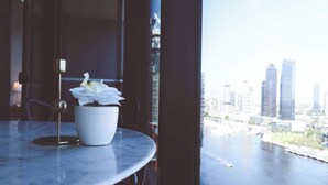 A potted orchid on a marble table by a window with a cityscape view. - KozyGuru | Docklands | Waterfront Skyline Retreat (Docklands)