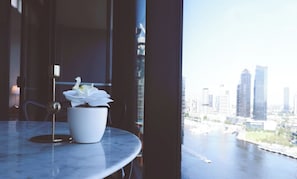 Eine Topf-Orchidee auf einem Marmortisch neben einem Fenster mit Blick auf die Stadt.
