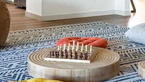 Eine moderne Küche mit weißen Schränken, einem Edelstahlkühlschrank und einer Wanddekoration aus gewebtem Material.