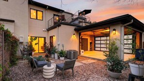 A modern house with a covered patio, outdoor seating, and a garage.