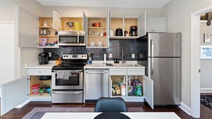 A compact kitchen with built-in appliances, open shelving, and a small dining area. - Beltline Cottage • Walk to Ponce City Market (Atlanta)
