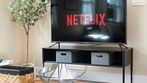 A television with a Netflix logo on the screen, placed on a black stand with storage drawers. - Beltline Cottage • Walk to Ponce City Market (Atlanta)