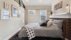 A bedroom with a bed, a window, a fireplace, and wall art. - Beltline Cottage • Walk to Ponce City Market (Atlanta)