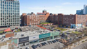 A multi-story building with a prominent red brick facade, a large parking lot, and a medical facility with a green sign. - Beltline Cottage • Walk to Ponce City Market (Atlanta)