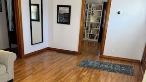 Una habitación con suelo de madera, un sofá, una alfombra y una estantería.