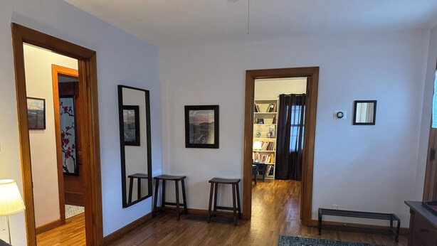 Una habitación con piso de madera, un sofá, una mesita, un tapete y una estantería.