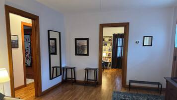 Une pièce avec un plancher en bois, un canapé, une petite table, un tapis et une bibliothèque.
