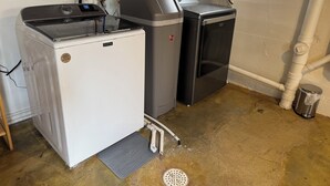 Un lavadero pequeño y funcional con calentador de agua, refrigerador compacto y sistema de filtrado de agua.